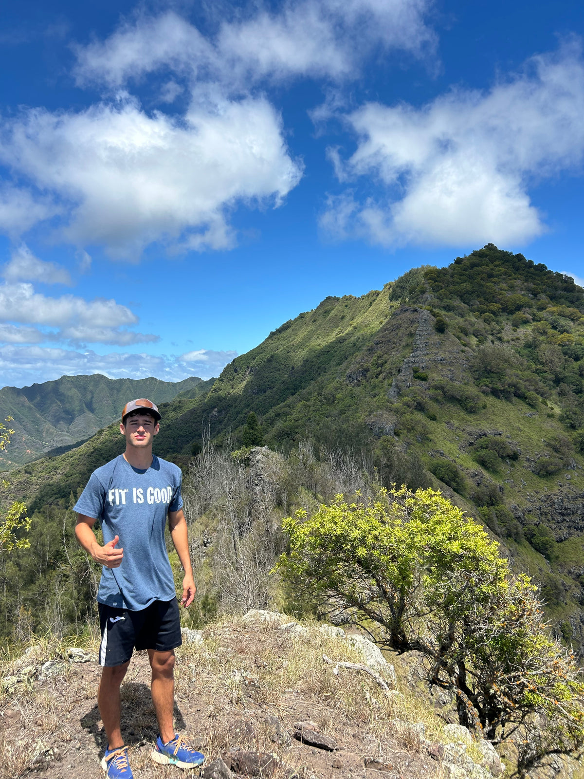 FIT IS GOOD Tee in Heather Blue worn on a mountain ridge in Oahu, Hawaii